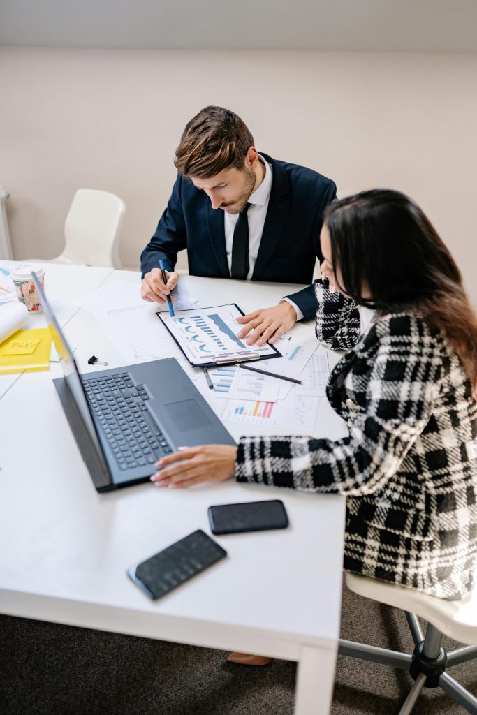 Deux professionnels de la finance analysent des données et collaborent à une planification financière à long terme dans un environnement de bureau moderne.